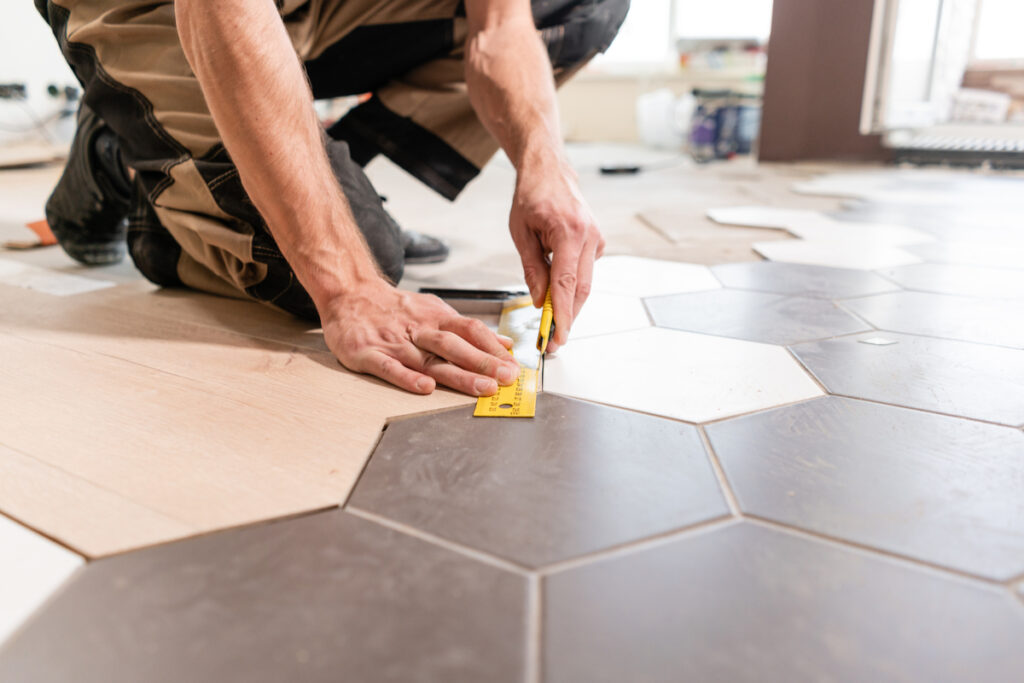 Man taking measurements and laying tiles
